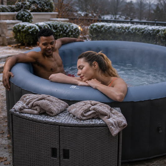 Two people relaxing in a Bergen MSpa hot tub outdoors with a Wicker Cabinet Round during cold winter day - portable sps NZ