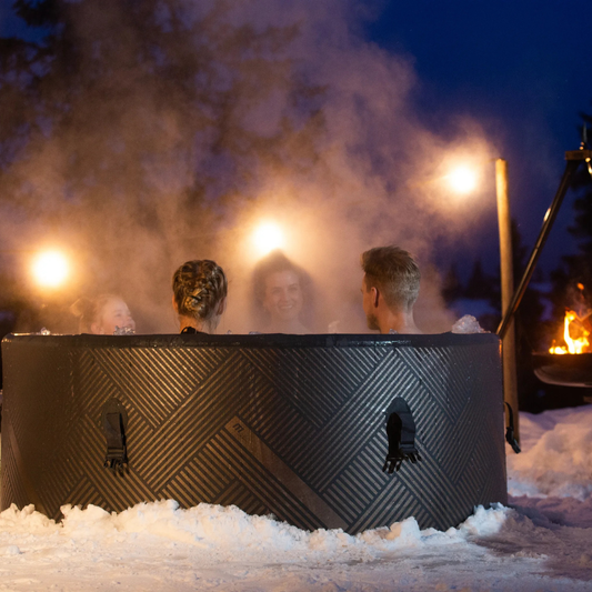 Family in a hot tub outdoors at night with lights and snow around - portable spas NZ
